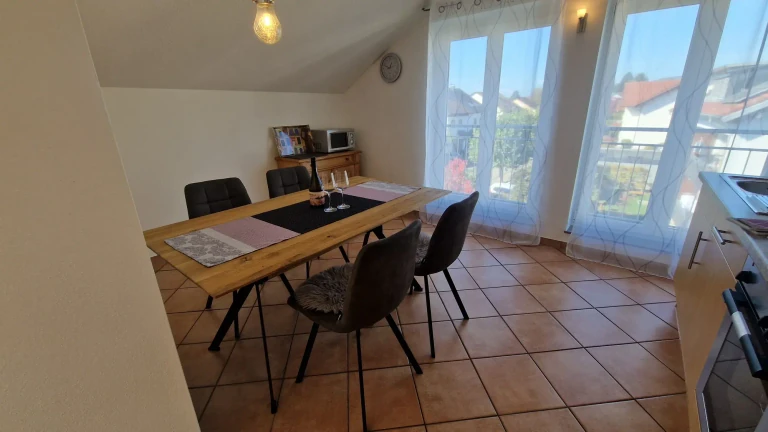 Heller Essbereich der Ferienwohnung Pfänder mit großem Tisch und Blick zum Balkon